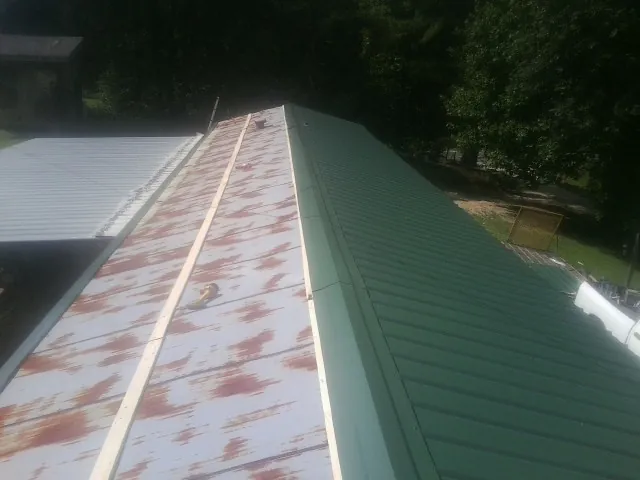 Old rusted panels beside newly installed green metal roofing — Wind Damage Roof Repair by Roofing Brothers in Chinook
