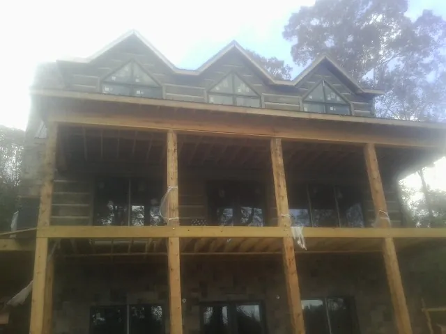 Dormers and porch framing on a large log home under construction — Roof Coating work by our crew in Chinook
