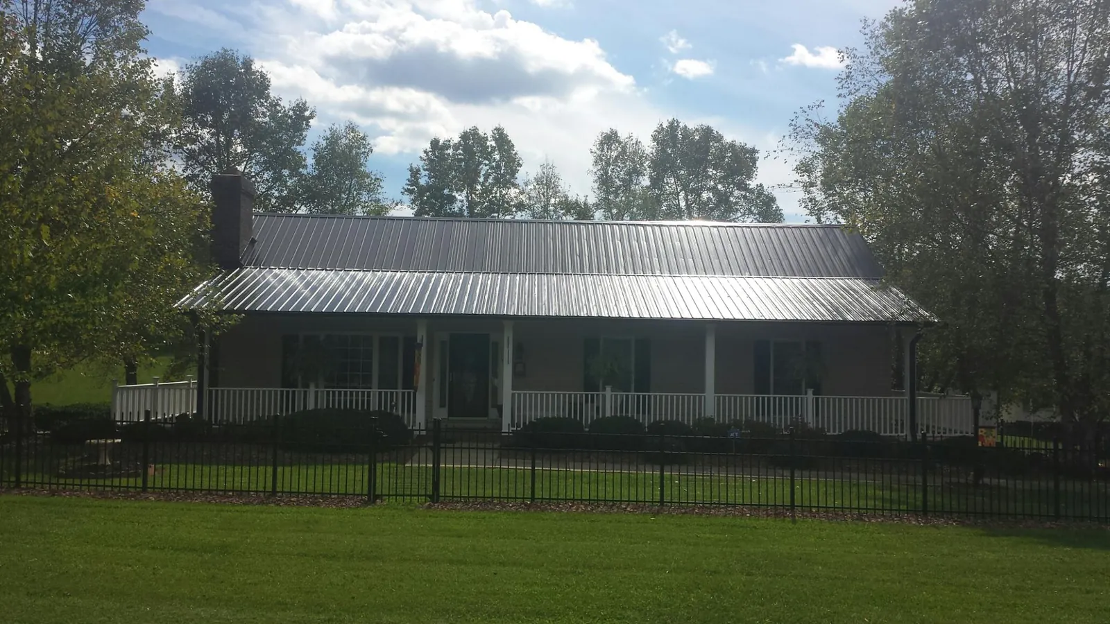 Gray metal roof on a brick ranch with a full width front porch — Gutter Guard Installation work by our crew in Chinook