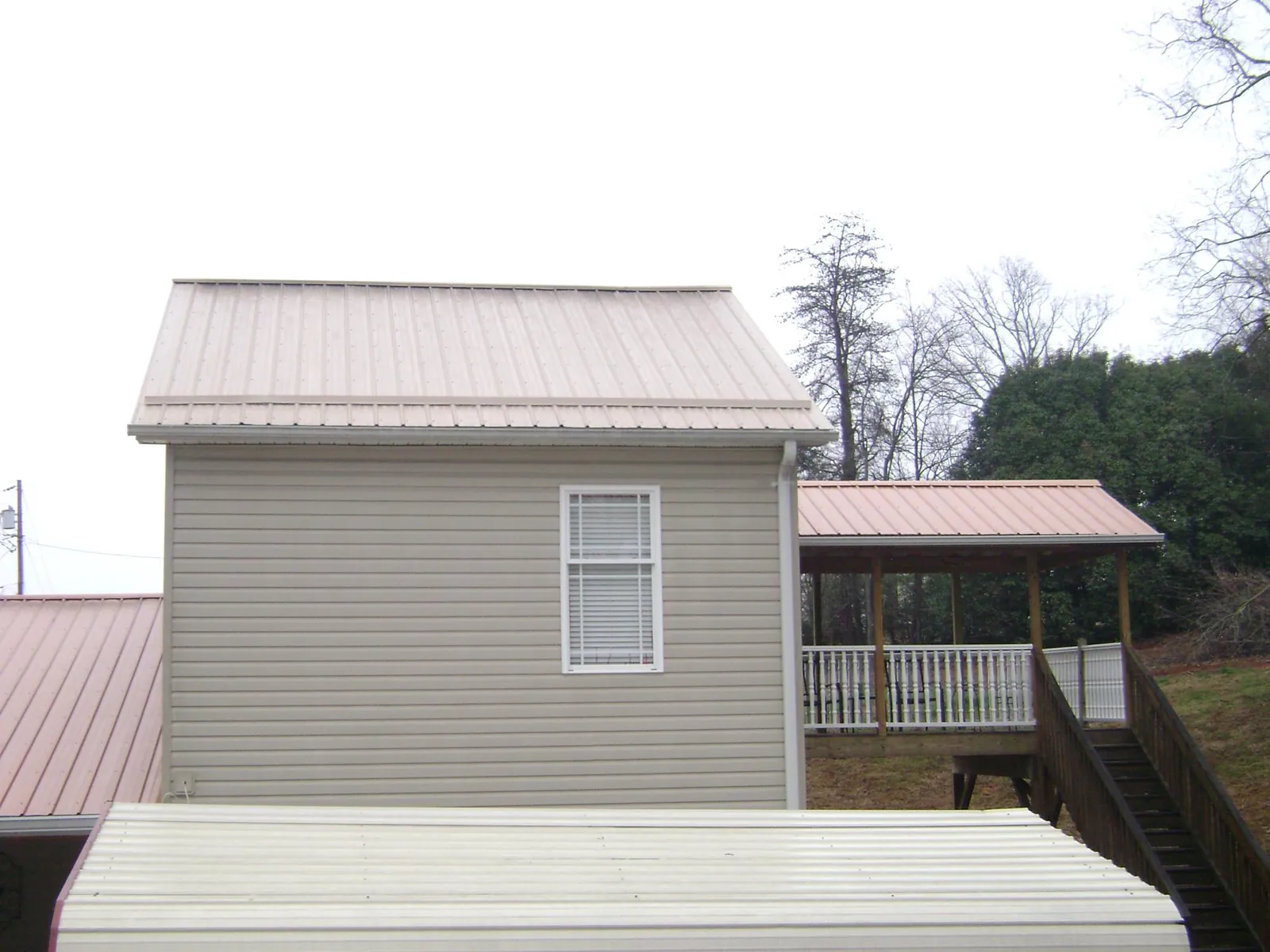 Tan metal roofs on a two story addition and attached porch, from a Roof Replacement job in Chinook