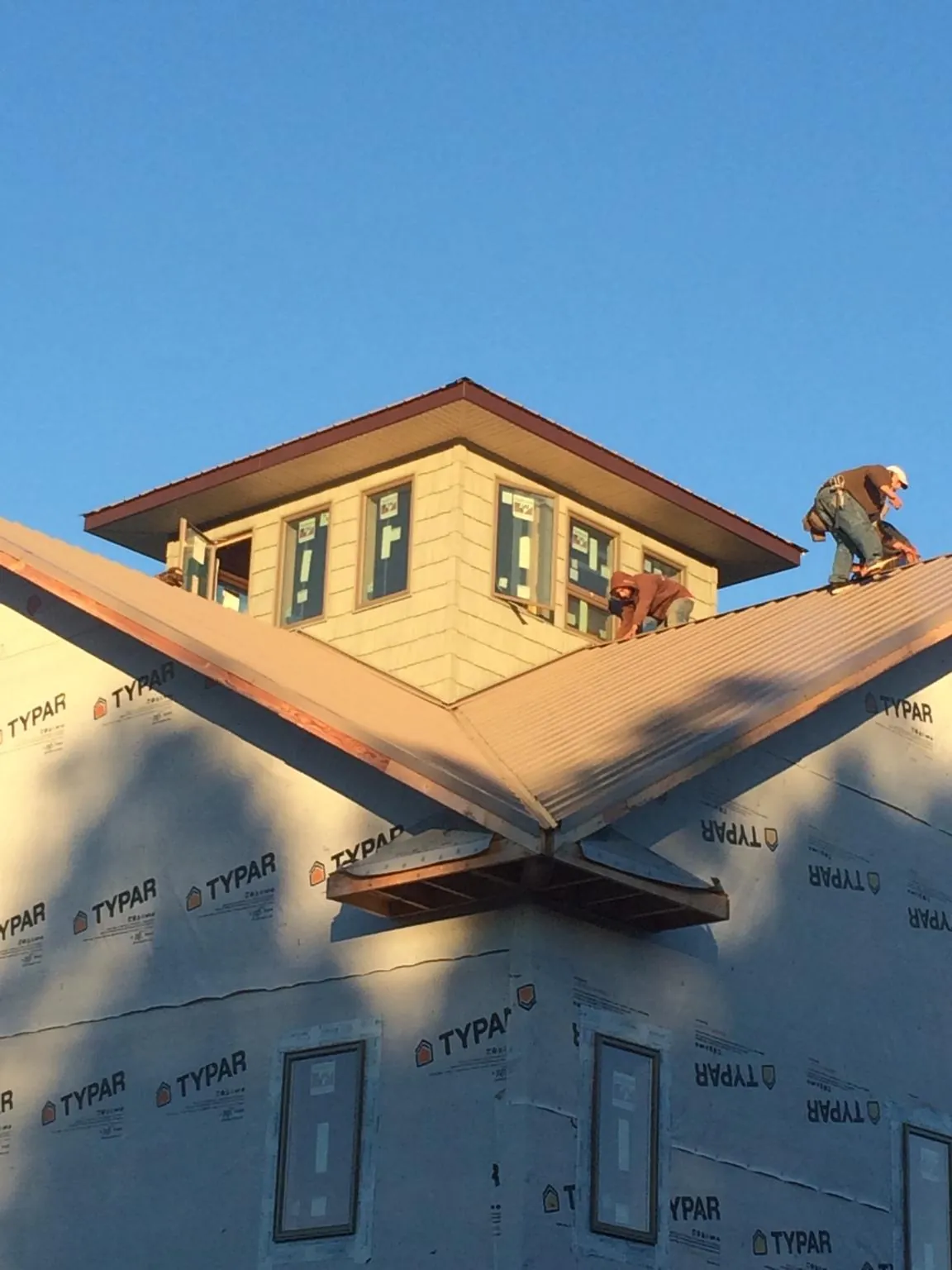 Roofers working around a rooftop cupola on a new metal roof at sunset — Roof Waterproofing in Chinook by Roofing Brothers